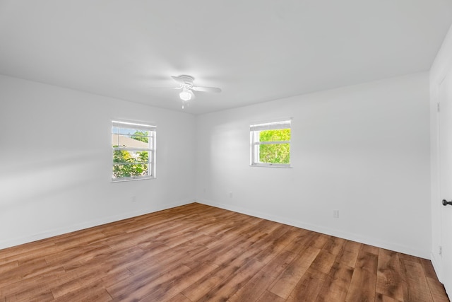 empty room featuring baseboards, wood finished floors, and a ceiling fan