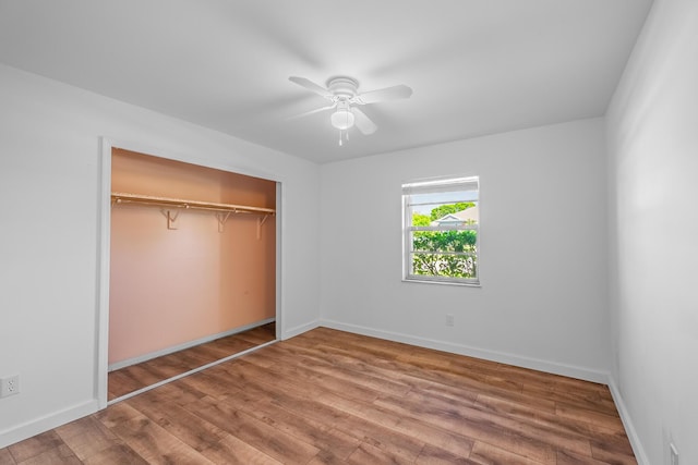 unfurnished bedroom with ceiling fan, wood finished floors, a closet, and baseboards