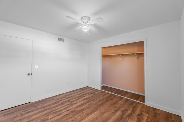unfurnished bedroom featuring a ceiling fan, wood finished floors, visible vents, and a closet