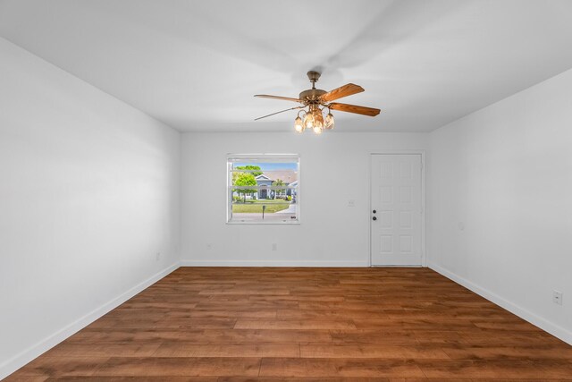 spare room with baseboards, wood finished floors, and a ceiling fan