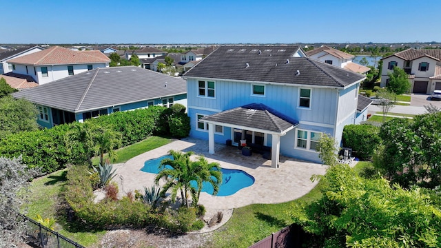 rear view of property with a fenced backyard, a residential view, a tiled roof, and a patio