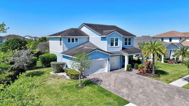 view of front of home featuring decorative driveway, an attached garage, a front lawn, and a tiled roof