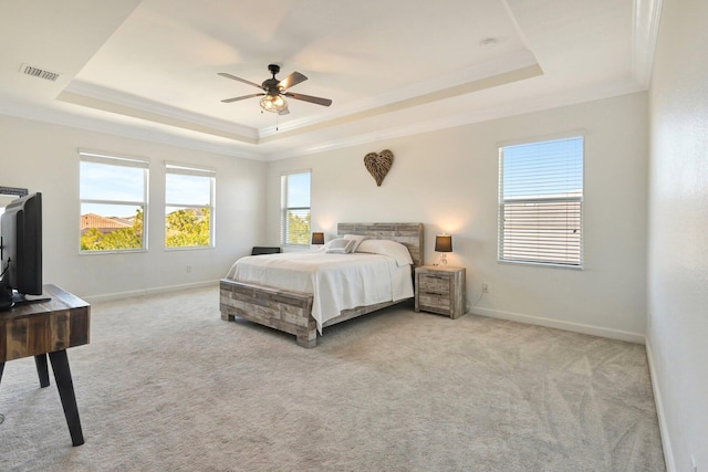 bedroom with visible vents, baseboards, a tray ceiling, ornamental molding, and light carpet