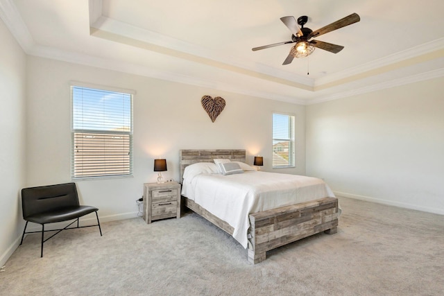 bedroom featuring a tray ceiling, light carpet, baseboards, and crown molding