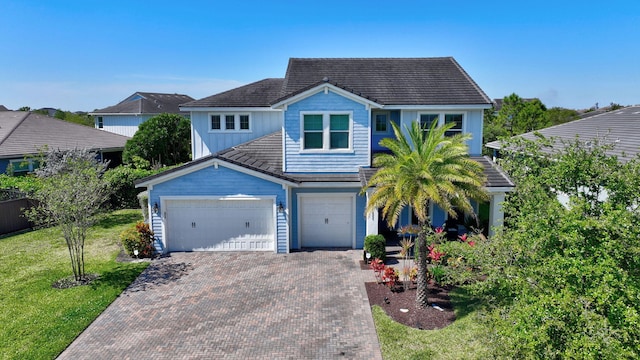 view of front of home featuring an attached garage, decorative driveway, a front lawn, and board and batten siding