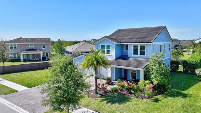 view of front of property with a front lawn, fence, a tile roof, and a residential view