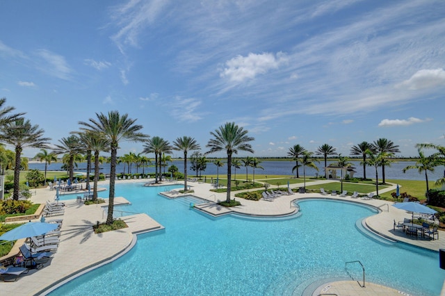 community pool with a yard, a water view, and a patio area