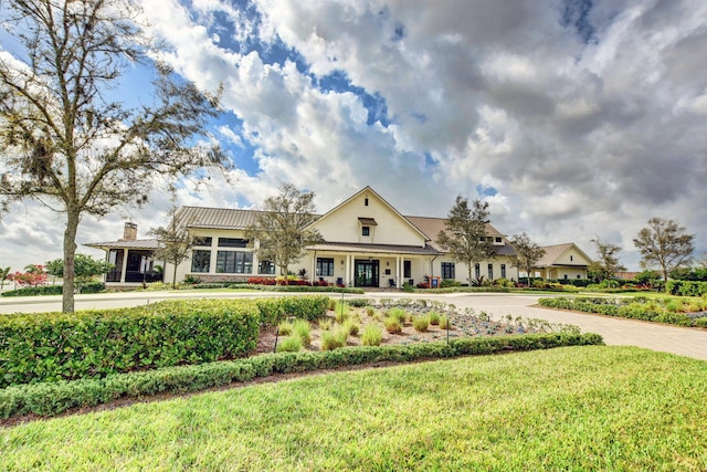 view of front of house featuring metal roof and a front lawn