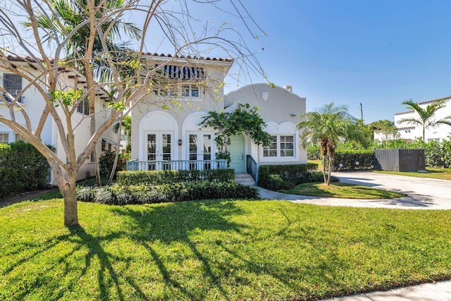 mediterranean / spanish home with a front yard, fence, a porch, stucco siding, and concrete driveway