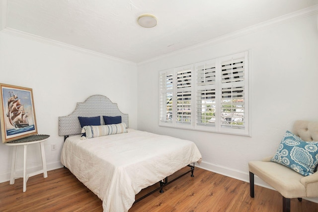 bedroom featuring wood finished floors, baseboards, and ornamental molding