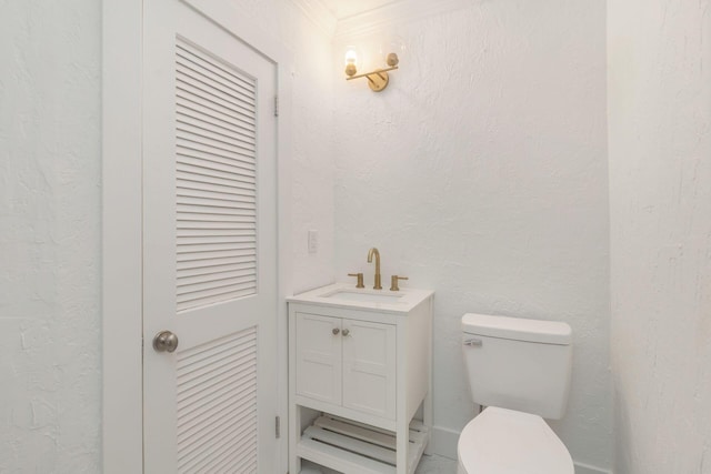 half bath with toilet, vanity, and a textured wall