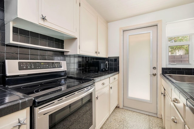 kitchen with backsplash, black microwave, tile countertops, stainless steel range with electric cooktop, and light speckled floor