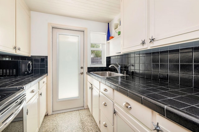 kitchen featuring tile countertops, light speckled floor, black microwave, and a sink