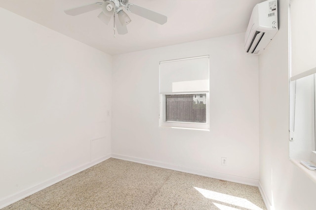 spare room with ceiling fan, baseboards, speckled floor, and a wall unit AC