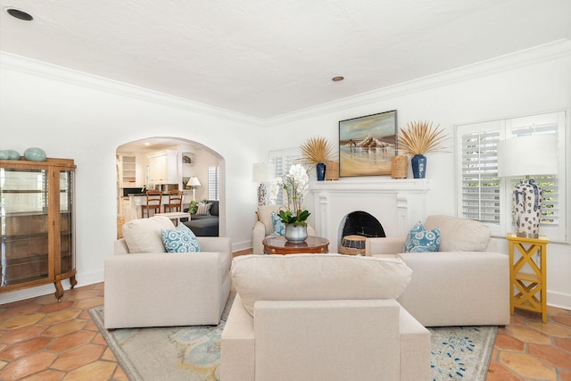 living room featuring crown molding, a fireplace, arched walkways, and baseboards