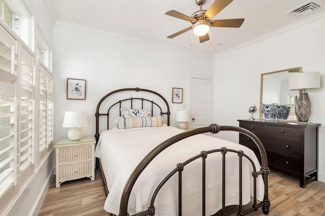 bedroom featuring visible vents, light wood-type flooring, a ceiling fan, and ornamental molding