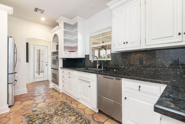 kitchen with visible vents, a sink, white cabinetry, appliances with stainless steel finishes, and decorative backsplash