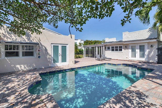 pool with french doors, a patio, and a sunroom