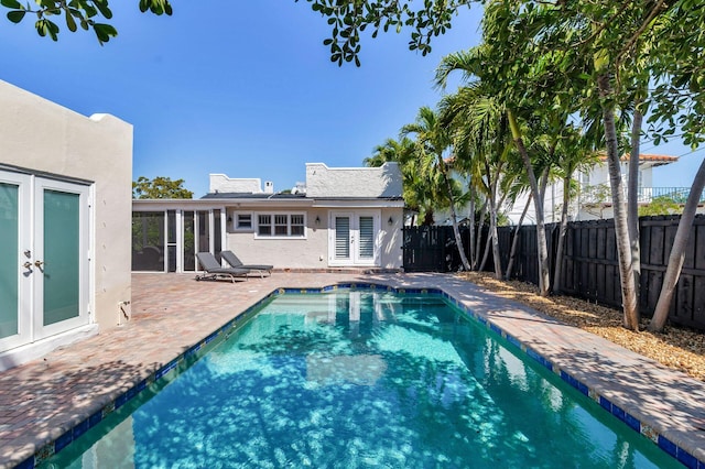 view of pool featuring a patio area, french doors, a fenced in pool, and a fenced backyard