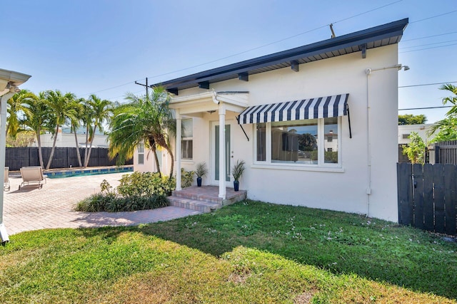 view of front facade with stucco siding, a fenced in pool, a front yard, and fence