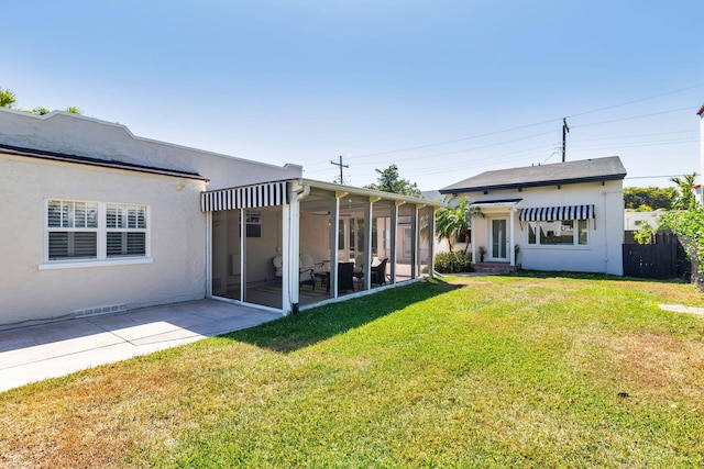 back of property with stucco siding, fence, a lawn, and a sunroom