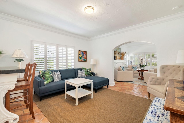 living area featuring arched walkways, light tile patterned flooring, and crown molding