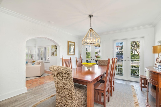 dining space featuring crown molding, baseboards, french doors, an inviting chandelier, and arched walkways