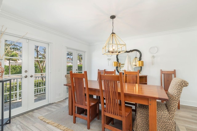 dining space featuring light wood finished floors, baseboards, ornamental molding, french doors, and a notable chandelier