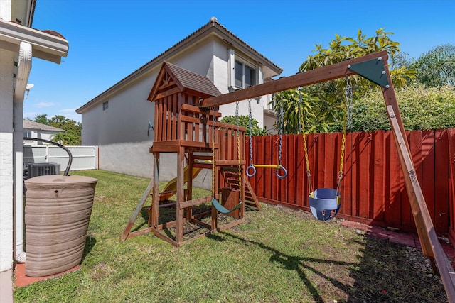 view of play area with central air condition unit, fence, and a lawn