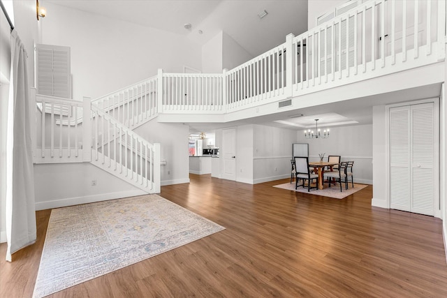 interior space with baseboards, stairway, a high ceiling, an inviting chandelier, and wood finished floors