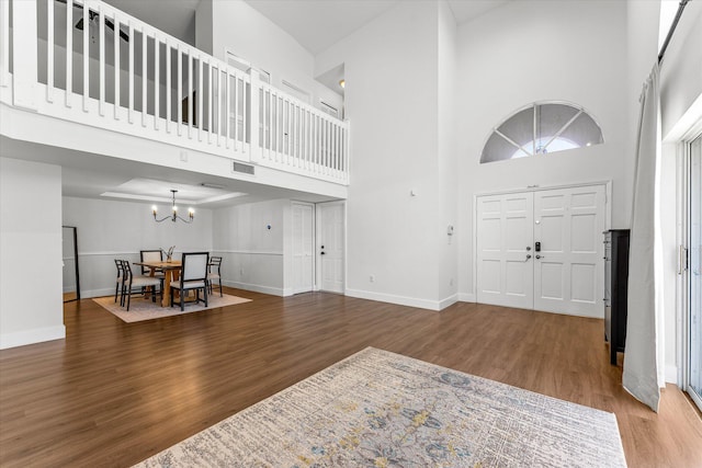 foyer entrance with visible vents, baseboards, a high ceiling, an inviting chandelier, and wood finished floors