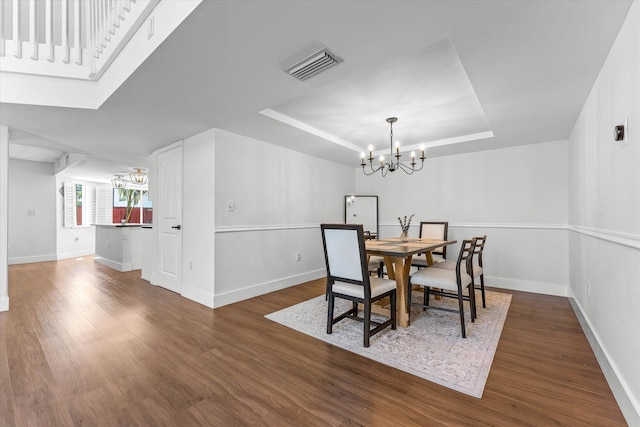 dining room with an inviting chandelier, a tray ceiling, wood finished floors, and visible vents