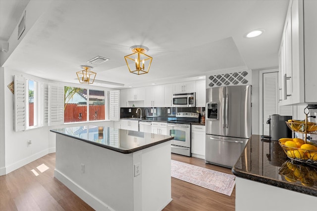 kitchen with a sink, wood finished floors, visible vents, and stainless steel appliances