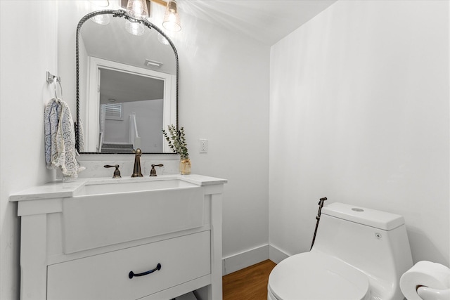 bathroom featuring vanity, toilet, wood finished floors, and baseboards