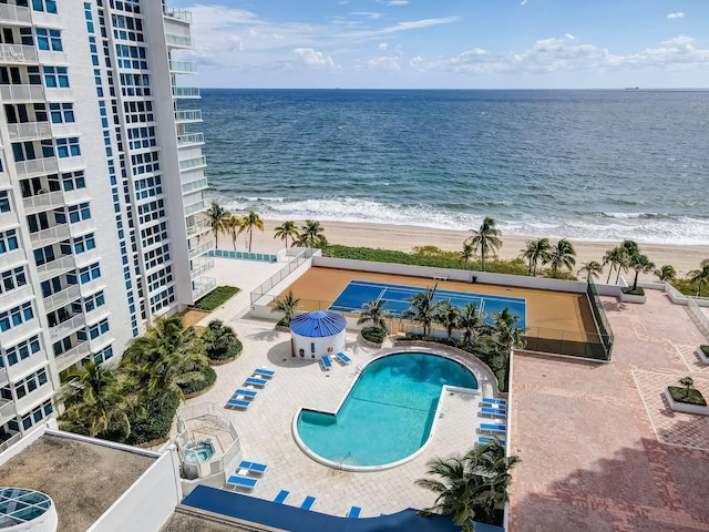 community pool with a view of the beach, a water view, and a patio