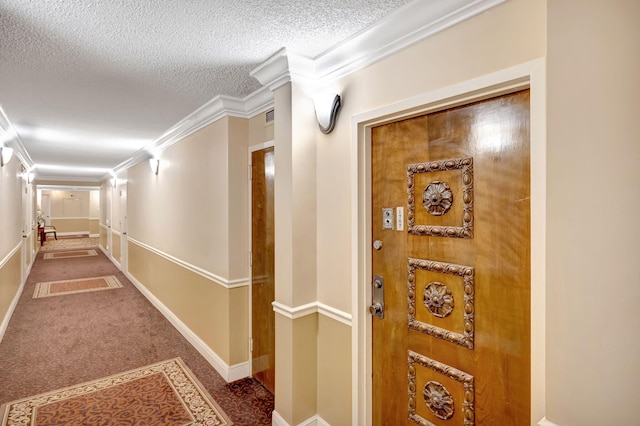 hall featuring ornamental molding, baseboards, carpet floors, and a textured ceiling