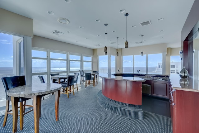 kitchen with hanging light fixtures, visible vents, dark brown cabinets, and a center island