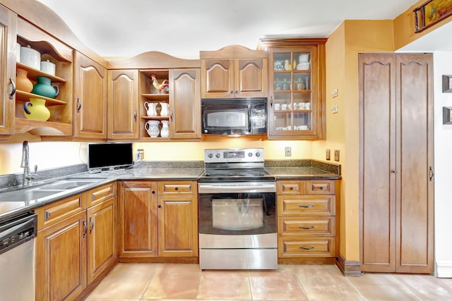 kitchen featuring open shelves, glass insert cabinets, brown cabinets, stainless steel appliances, and a sink