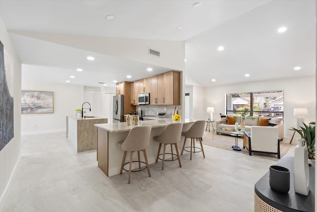 kitchen featuring tasteful backsplash, visible vents, a center island with sink, appliances with stainless steel finishes, and a sink