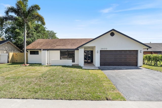 ranch-style home featuring a front lawn, fence, stucco siding, a garage, and driveway