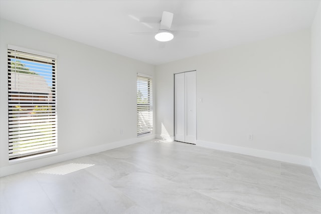 unfurnished room with a ceiling fan and baseboards