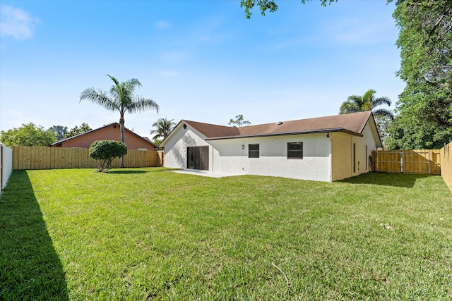 rear view of house with a yard, a fenced backyard, and stucco siding