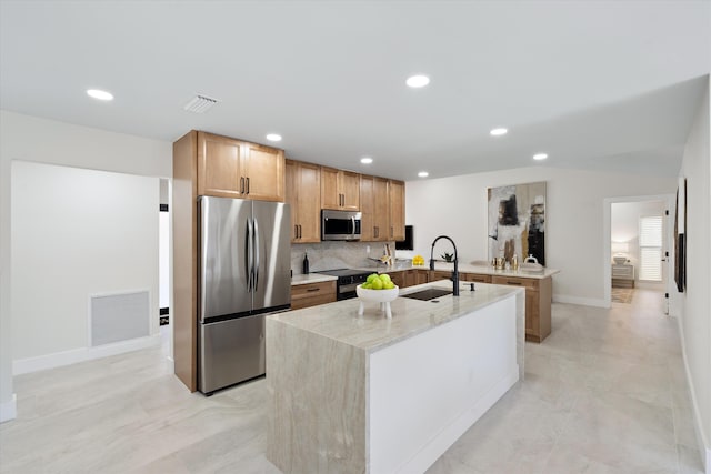 kitchen featuring a sink, stainless steel appliances, visible vents, and a center island with sink