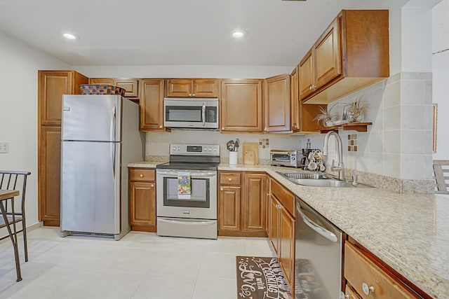 kitchen featuring a sink, stainless steel appliances, brown cabinetry, and light tile patterned floors