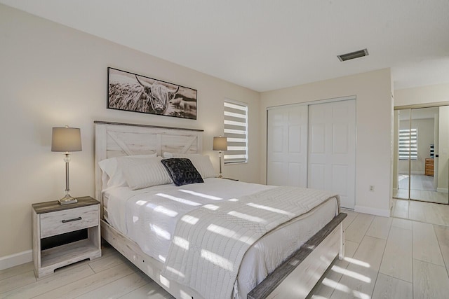 bedroom featuring light wood-type flooring, a closet, baseboards, and visible vents