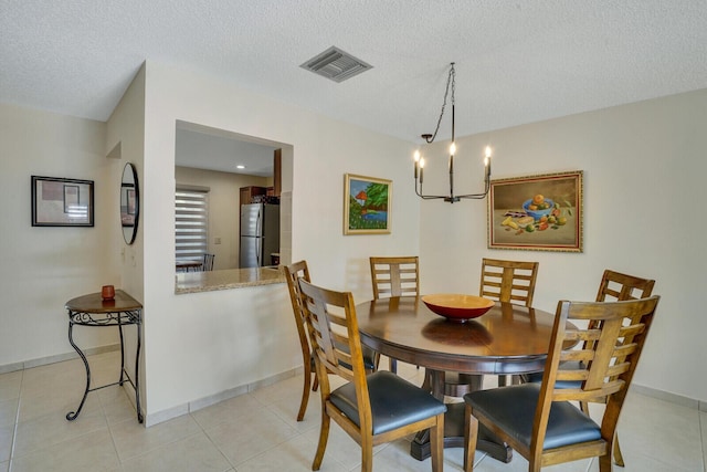 dining space featuring light tile patterned flooring, baseboards, visible vents, and a textured ceiling