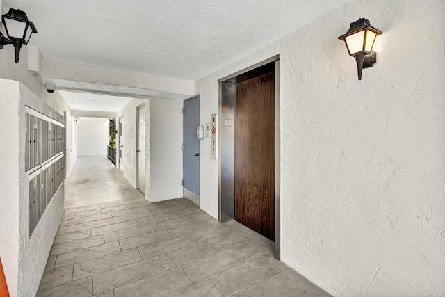 corridor with elevator, a textured ceiling, and a textured wall