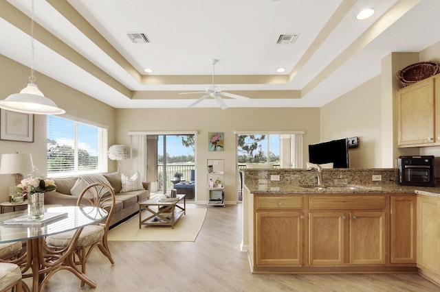 8290 Mulligan Cir Unit 2421, Port Saint Lucie, FL 34986 - kitchen with a raised ceiling, a sink, open floor plan, light wood-type flooring, and light stone countertops