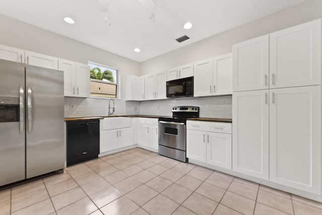 kitchen featuring visible vents, a sink, decorative backsplash, black appliances, and white cabinetry