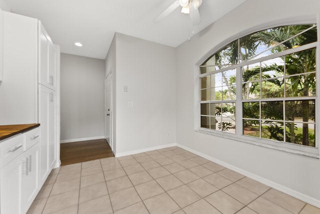 unfurnished dining area with baseboards, a healthy amount of sunlight, ceiling fan, and light tile patterned flooring